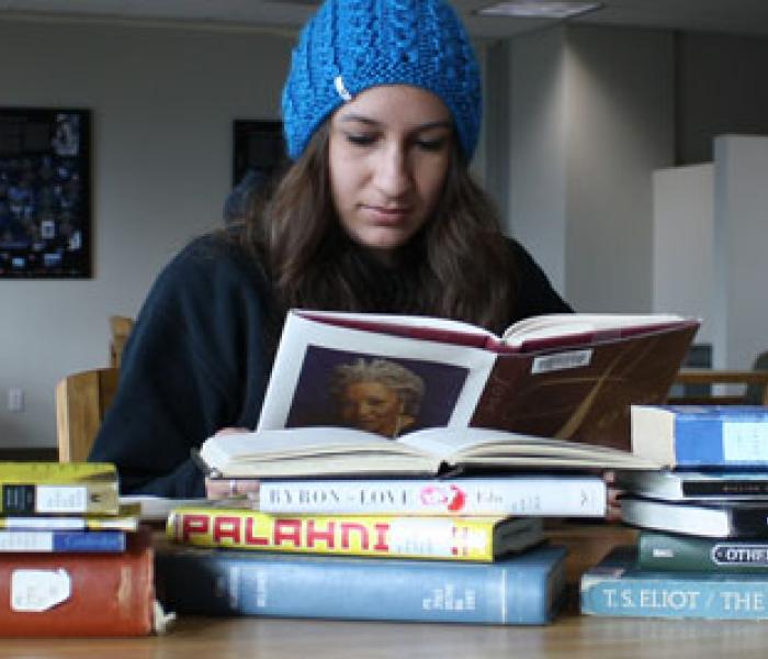Student reading books at a table in the library.