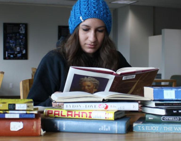 Student reading books at a table in the library.